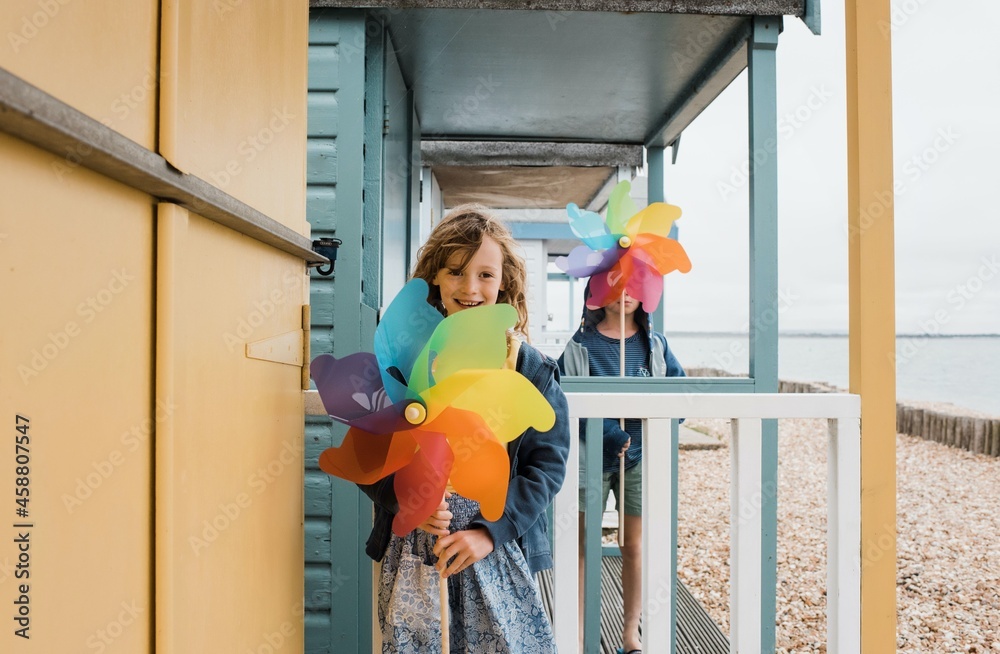 girl holding a windmill playing at beach huts at the seaside girl holding a windmill playing at beach huts at the seaside
