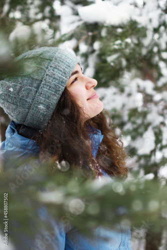 A portrait of a woman happily admiring the falling snow looks up. photo