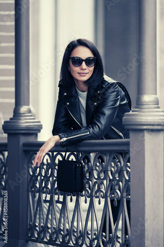 Young fashion woman in black leather jacket leaning on railing