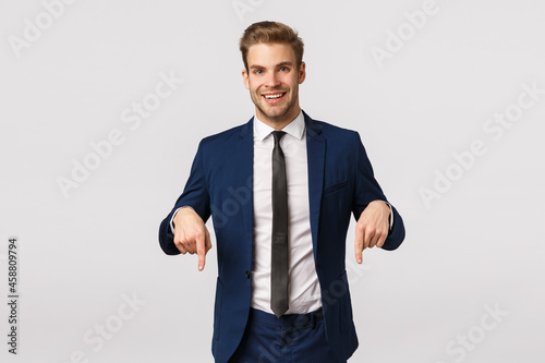Here is what you need. Handsome stylish happy businessman, blond bearded guy in classic suit, invite check out promo, pointing fingers down and smiling, have interesting corporate banner for you see photo
