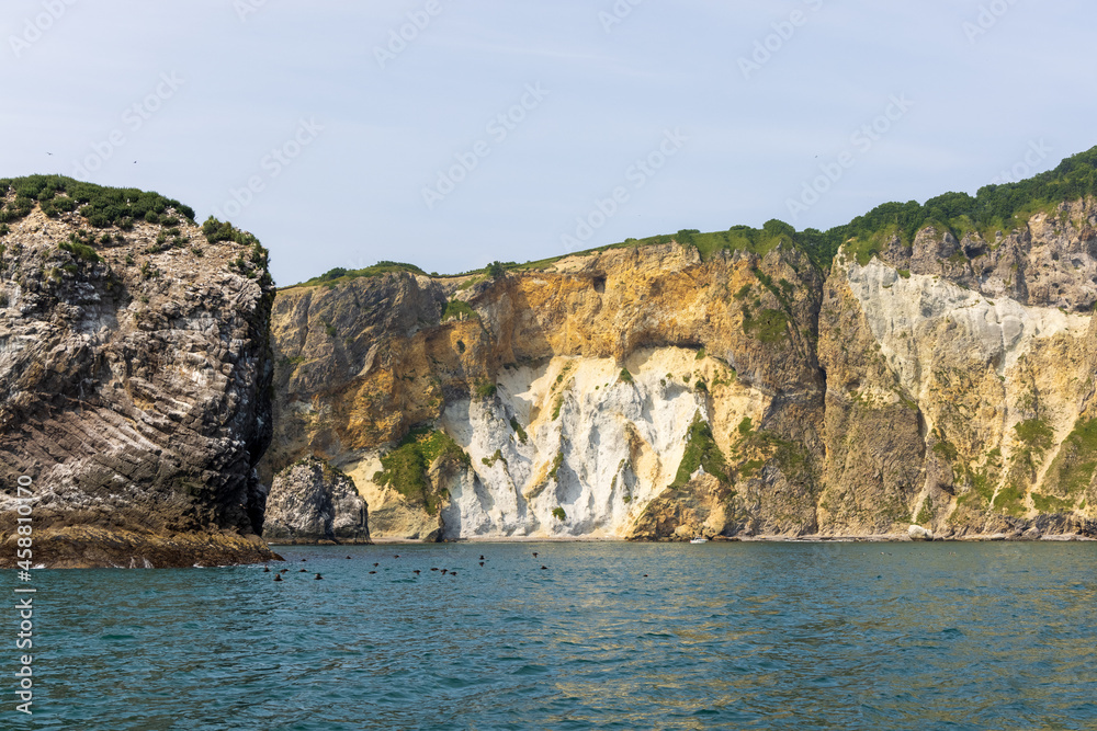 Cliffs of the steep coast of the Pacific Ocean in Kamchatka, interesting geological structures of the cliff.