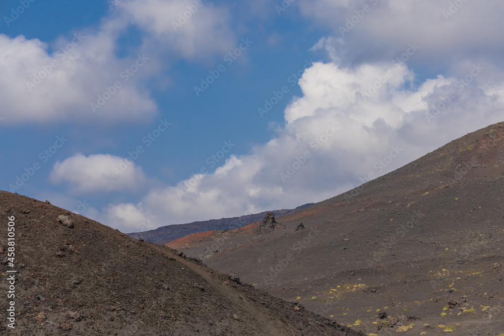 Volcanic-lunar landscape in Kamchatka, rocks from volcanic rocks against the background of a blue sky with clouds. Klyuchevskaya group of volcanoes. 