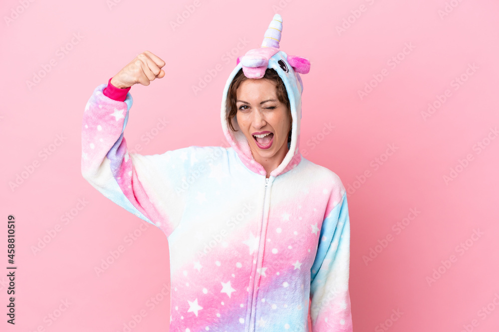 Young caucasian woman with unicorn pajamas isolated on pink background doing strong gesture Young caucasian woman with unicorn pajamas isolated on pink background doing strong gesture