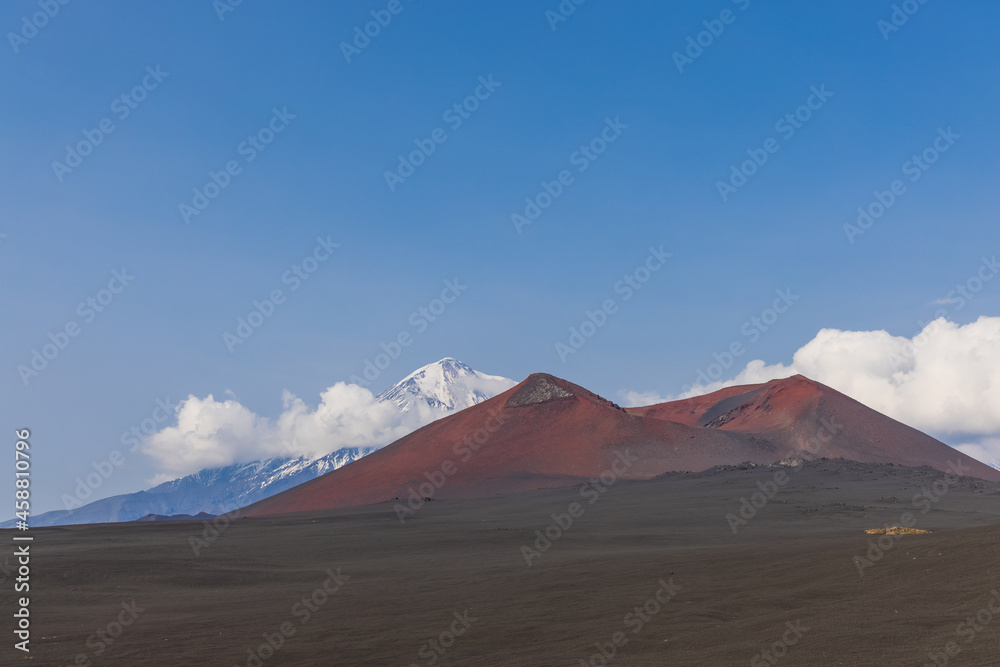 Volcanic-lunar landscape in Kamchatka, rocks from volcanic rocks against the background of a blue sky with clouds. Klyuchevskaya group of volcanoes. 