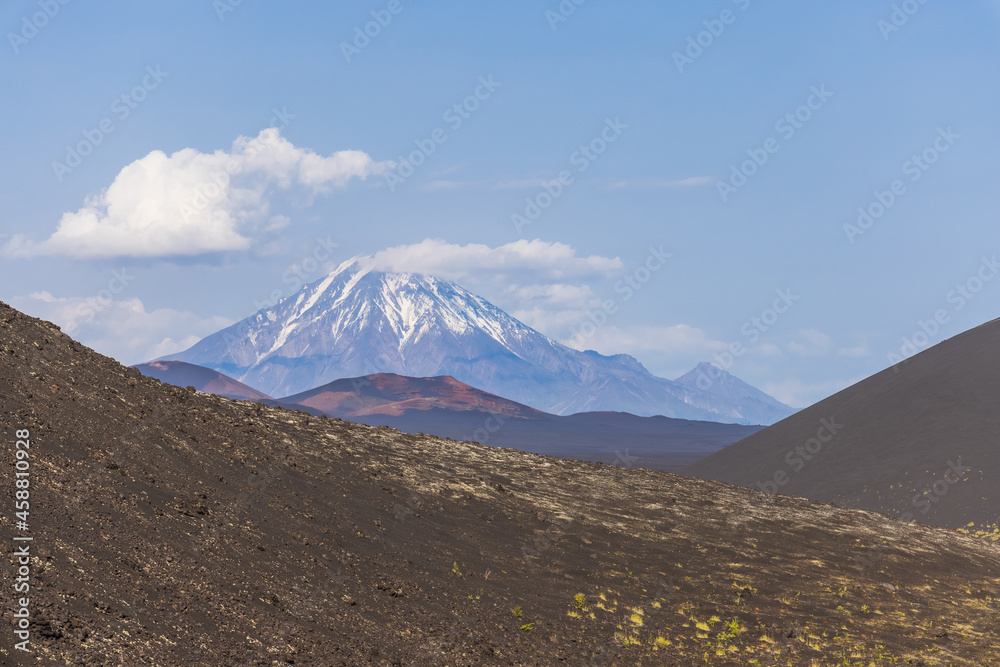 Kamchatka volcano. Volcanic-lunar landscape in Kamchatka, rocks from volcanic rocks against the background of a blue sky with clouds. Klyuchevskaya group of volcanoes.
