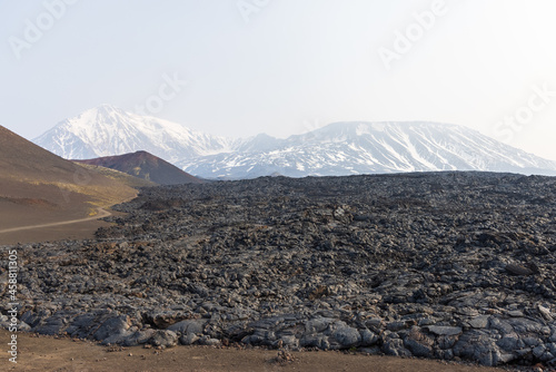 Kamchatka rocks from volcanic rocks multi-colored volcanic rocks. Crumbling volcano craters. against the backdrop of volcanoes with peaks in the snow and clouds. Ostry Tolbachik and Plosky Tolbachik.