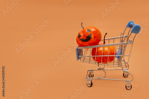 Orange pumpkins in a cart and scattered pumpkins on a beige background. flat lei on the topic of sale in halloween. copy space