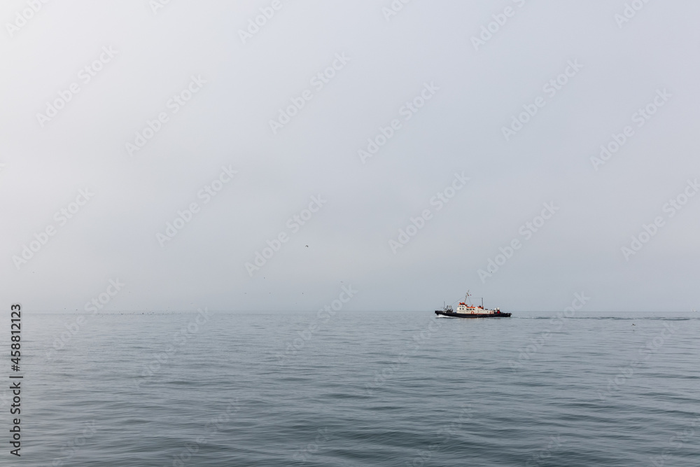 A lonely little ship sails along the calm,  foggy and misty Pacific Ocean in the Kamchatka