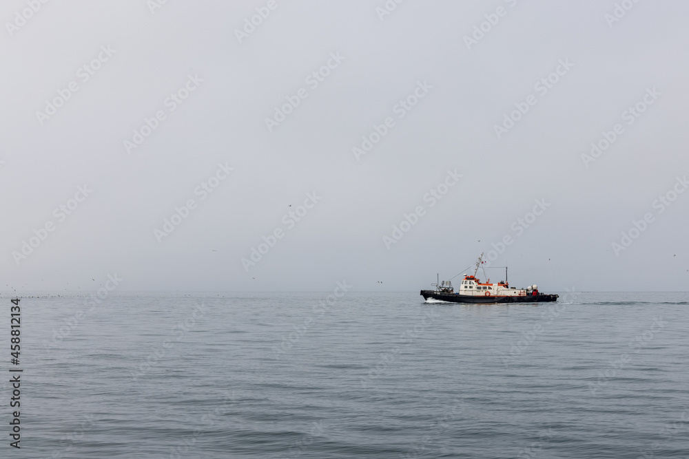A lonely little ship sails along the calm,  foggy and misty Pacific Ocean in the Kamchatka