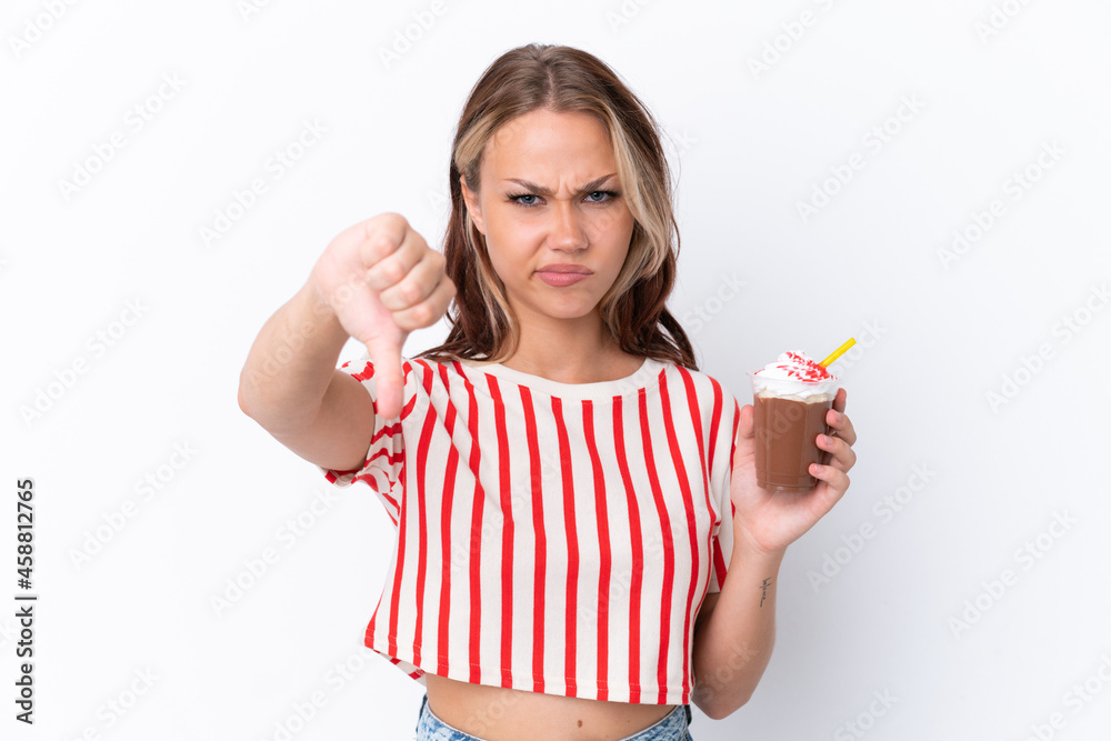 Young Russian girl holding cappuccino isolated on white background showing thumb down with negative expression Young Russian girl holding cappuccino isolated on white background showing thumb down with negative expression