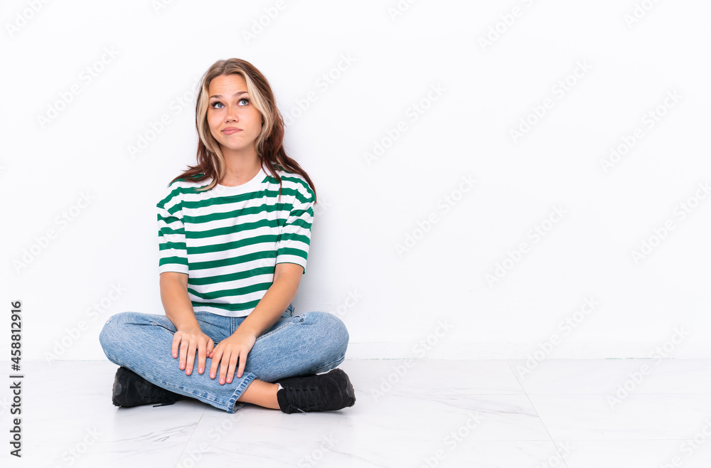 Young Russian girl sitting on the floor isolated on white background and looking up