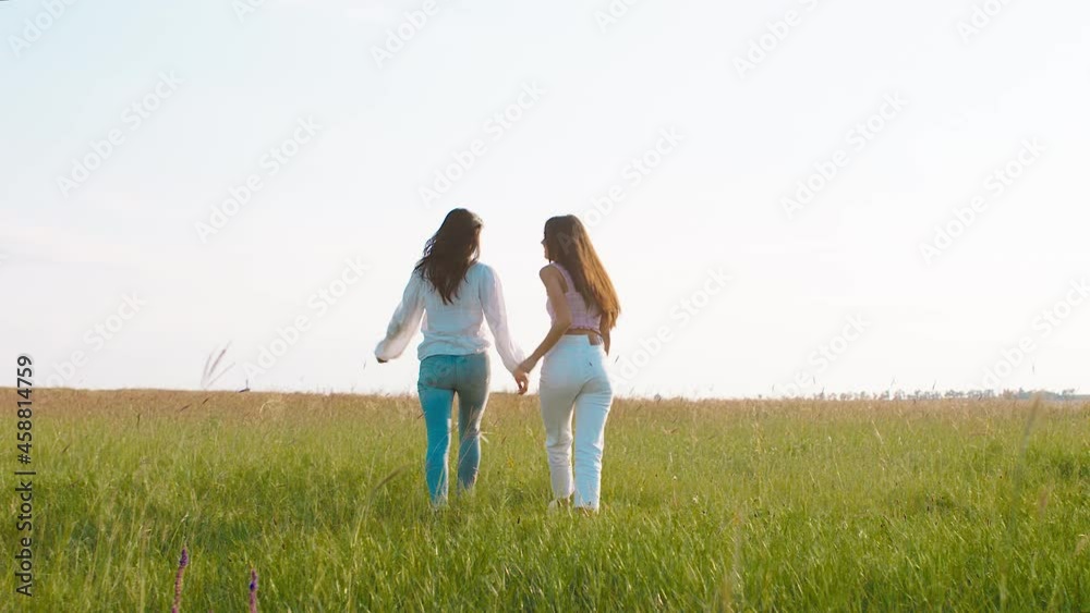 At nature in the middle of a large field beautiful two ladies walking down the field and enjoy the landscape around them At nature in the middle of a large field beautiful two ladies walking down the field and enjoy the landscape around them