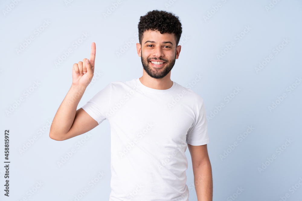 Young Moroccan man isolated on blue background pointing up a great idea Young Moroccan man isolated on blue background pointing up a great idea