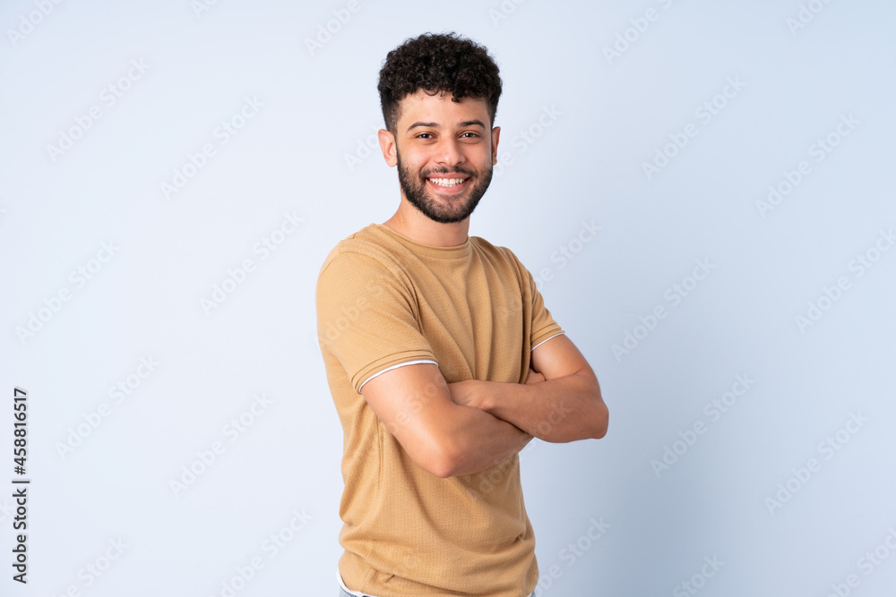 Young Moroccan man isolated on blue background with arms crossed and looking forward Young Moroccan man isolated on blue background with arms crossed and looking forward