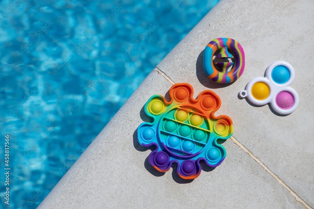 Anti-stress toys pop it, simple dimple, snapperz on side of pool, copy space. Concept trendy entertainment for fidget children, sensory toys for development of fine motor skills, stress relieving