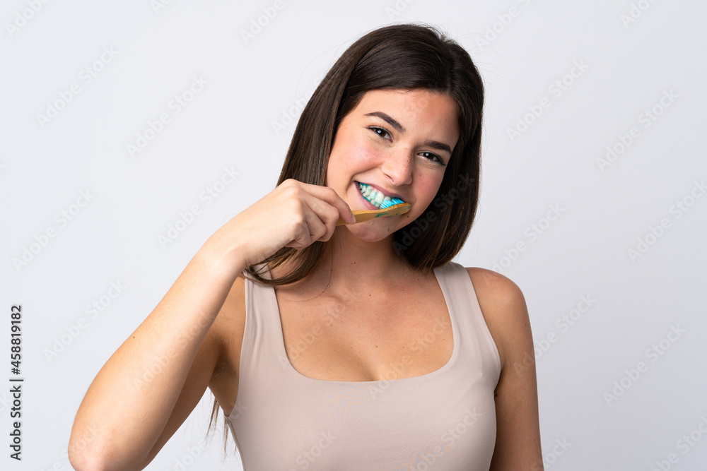 Teenager Brazilian girl brushing her teeth over isolated white background Teenager Brazilian girl brushing her teeth over isolated white background