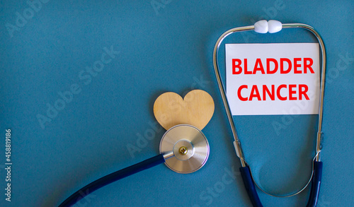 Bladder cancer symbol. White card with words Bladder cancer, beautiful blue background, wooden heart and stethoscope. Medical and bladder cancer concept.