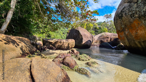 Praia com água cristalina no litoral paulista e pedras 