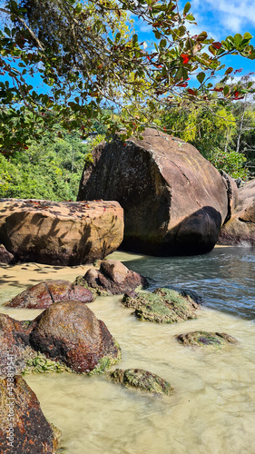 Praia com água cristalina no litoral paulista e pedras 