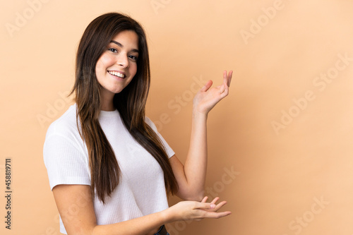 Teenager Brazilian girl over isolated background extending hands to the side for inviting to come