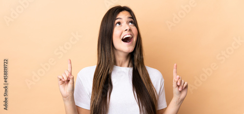Teenager Brazilian girl over isolated background surprised and pointing up