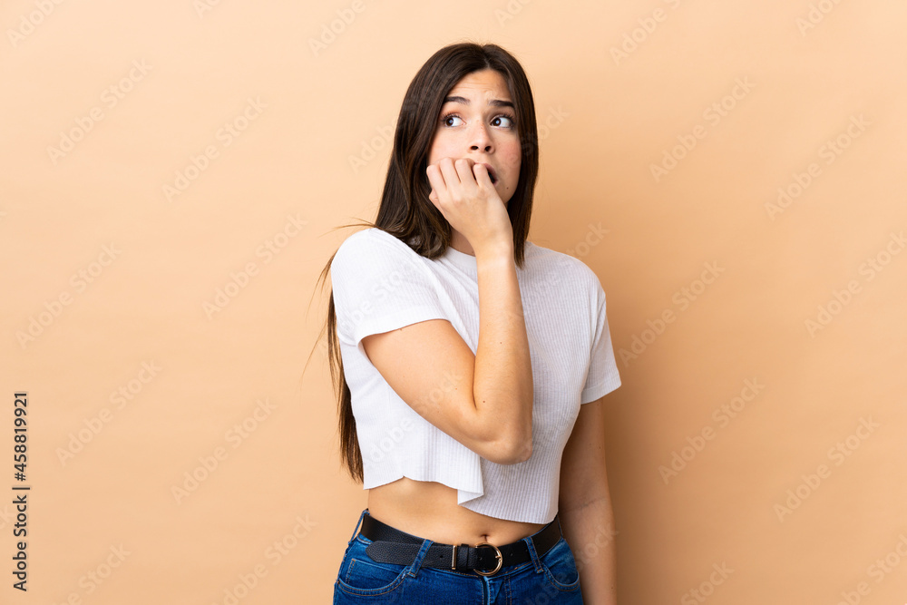 Teenager Brazilian girl over isolated background is a little bit nervous Teenager Brazilian girl over isolated background is a little bit nervous