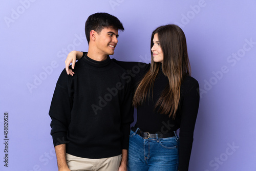 Young couple over isolated purple background happy and laughing