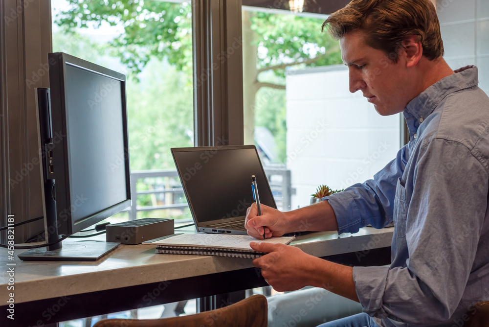 Young man taking notes in modern home office Young man taking notes in modern home office