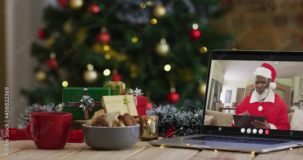 Senior african american man in santa costume on video call on laptop, with christmas tree Senior african american man in santa costume on video call on laptop, with christmas tree