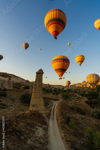 Vertical image of bunch of colorful hot air balloon flying early morning in Cappadocia, Turkey against typical rock formation due to volcanic activity in love valley located in Goreme national park