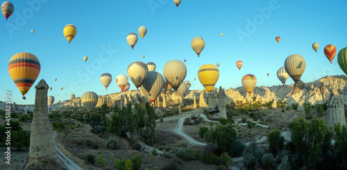 Panorama of bunch of colorful hot air balloon flying early morning in Cappadocia, Turkey against typical rock formation due to volcanic activity in love valley located in Goreme national park