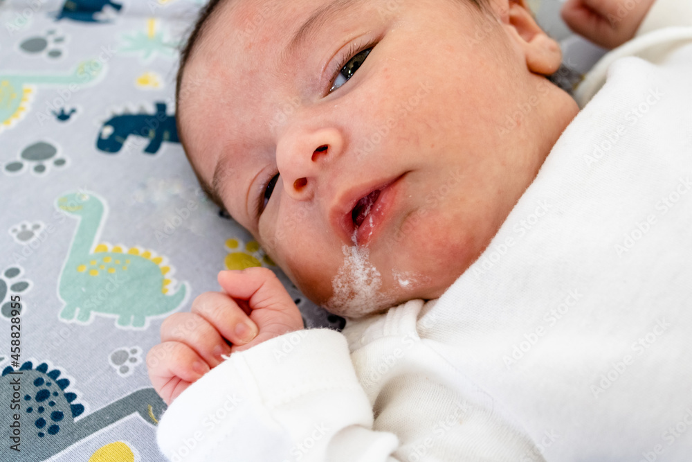 Newborn baby with reflux lying on a crib showing the dangers in cribs and the need for parental