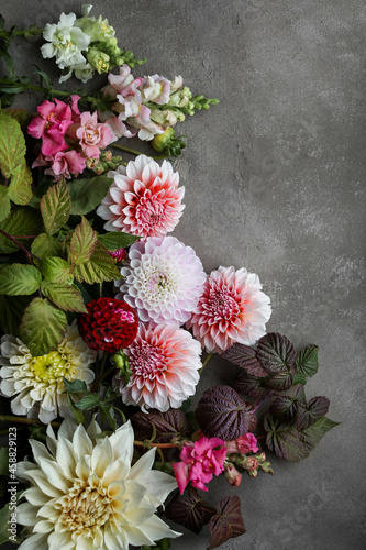 Different garden flowers on a gray-beige background. Dahlias, zinnias, antirriniums and asters lie on the table. Floral wallpapers and backgrounds. photo