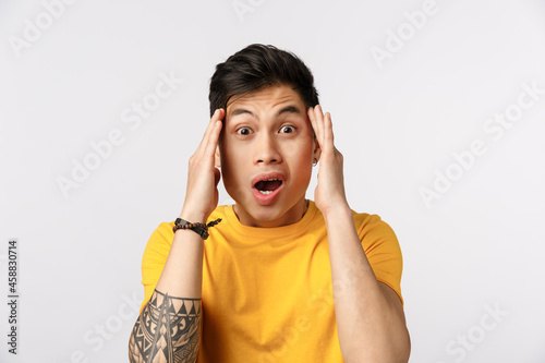 Guy going crazy from information, flipping out, losing his mind from realisation. Shocked and impressed asian guy touching temples and stare camera speechless, gasping, drop jaw shook