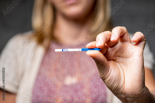 girl holding negative pregnancy test in her hands on gray background