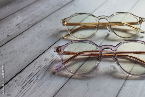 Glasses for vision in a plastic colored frame, with movable nose pads. A pair of panto-shaped eyeglasses lie on a wooden surfacepink. Eyesight accessory. Eyewear shop concept. Optical content