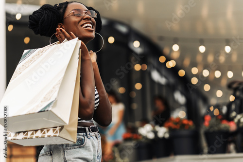Beautiful African woman, in the mall with shopping bags, happy woman doing Christmas shopping