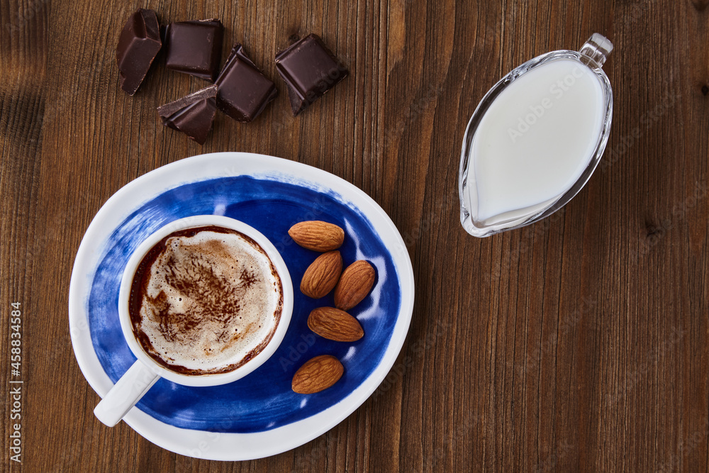 Cup of cappuccino almonds chocolate and milk in a glass milk jug Cup of cappuccino almonds chocolate and milk in a glass milk jug