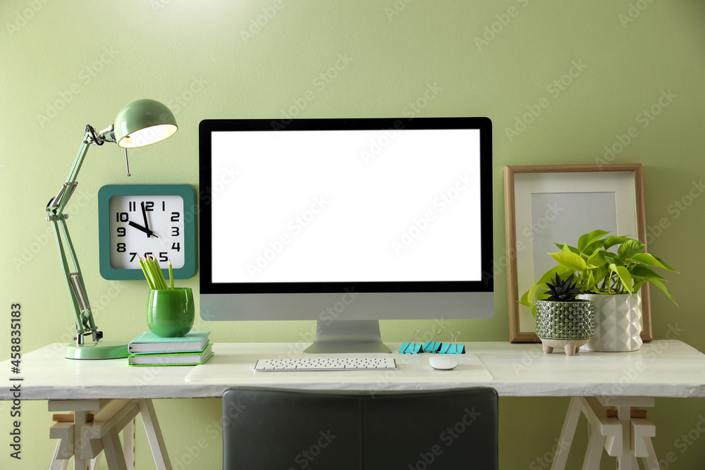 Stylish workplace with modern computer near light green wall indoors. Space for text Stylish workplace with modern computer near light green wall indoors. Space for text