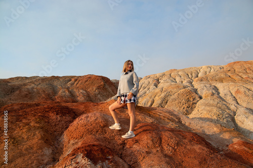 Fotografie a young blonde girl in casual clothes in the mountains of red clay
