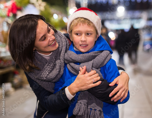 Portrait of happy tween boy and his loving mom during shopping at street fair on Christmas Eve..