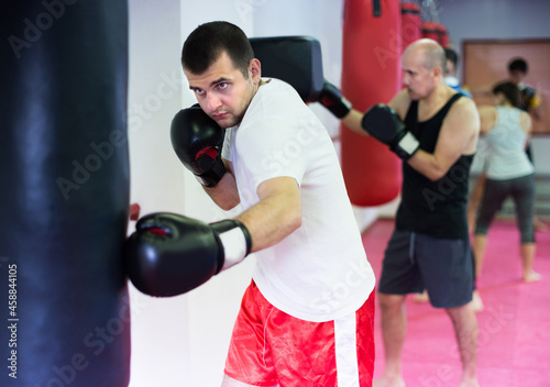 Sportsman is beating a boxing bag in the boxing hall. © JackF