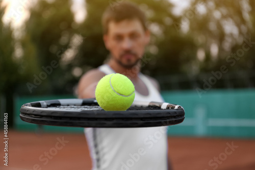 Handsome man playing tennis outdoors, focus on racket © New Africa