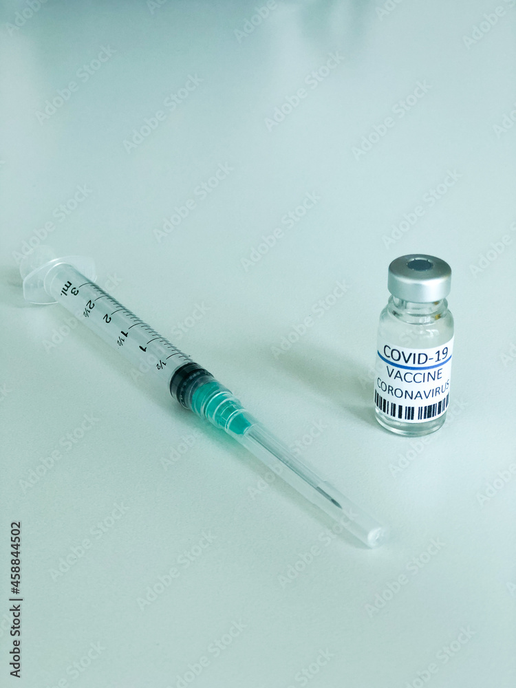 Dose of COVD-19 vaccine and a syringe Dose of COVD-19 vaccine and a syringe