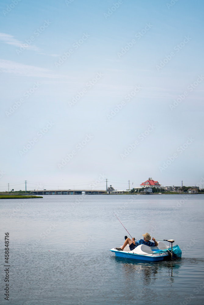 A man fishing on a plastic peddle and motorized electric boat relaxing and enjoying the peaceful sunny day on the water