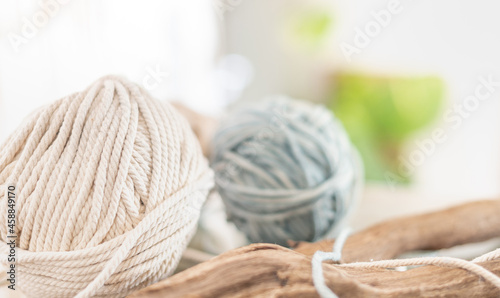 Balls of white and beige yarn on light wood table. Threads of high-quality wool for macrame and handicrafts.