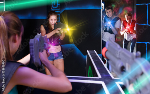 Two teams of girls and guys playing lasertag game opposite each other in labyrinth