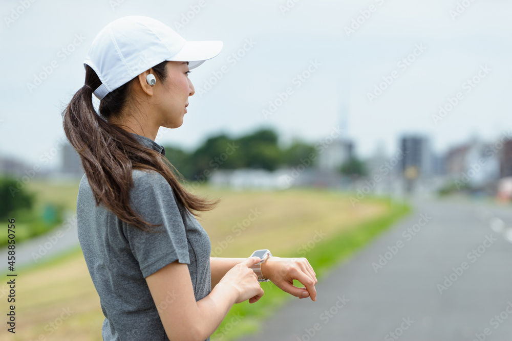 スマートウォッチを見てランニングをする女性 スマートウォッチを見てランニングをする女性