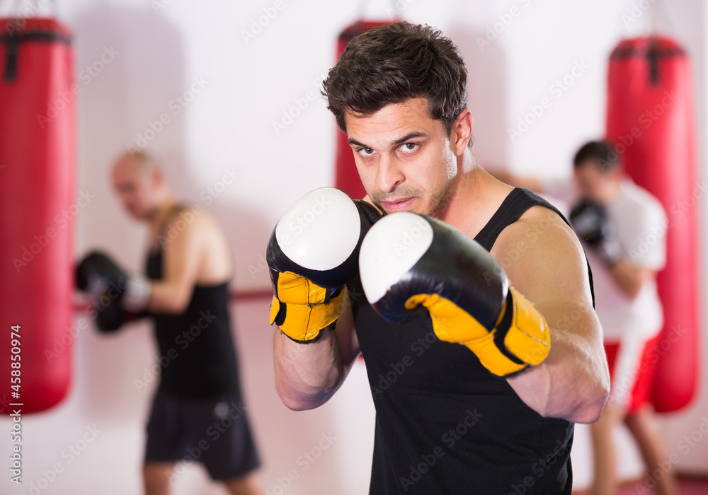 Young boxer trains in kickboxing gloves in the gym.