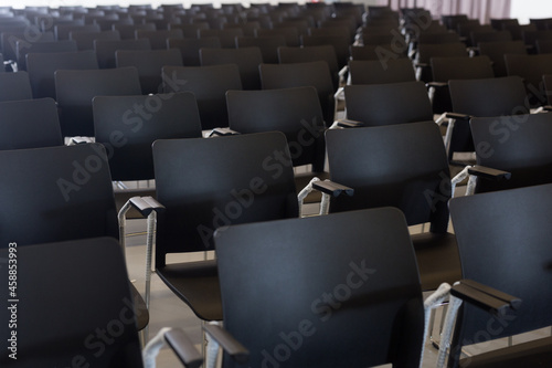 Empty conference hall with rows of black plastic chairs